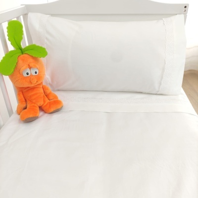 Cama de bebê com lençóis brancos e peluche laranja em madeira branca