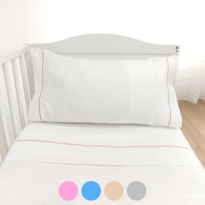 Conjunto de cama de bebé branco com frisos cor-de-rosa numa cama de bebé branca