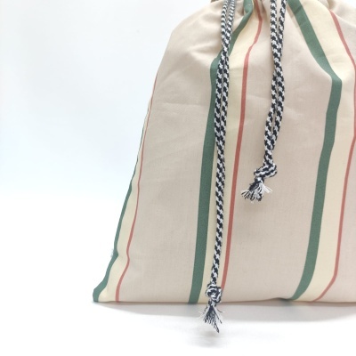 Mochila de tecido bege com riscas verdes e vermelhas e cordão de fecho preto e branco