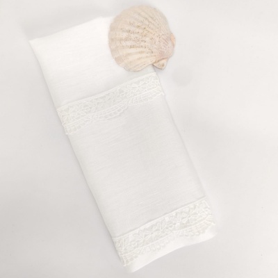 Toalha branca com bordado rendado e concha decorativa clara