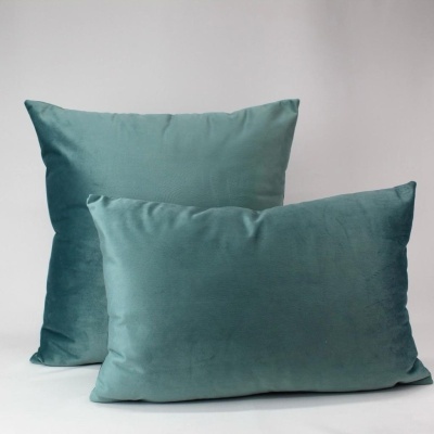 Duas almofadas de veludo azul esverdeado em fundo branco