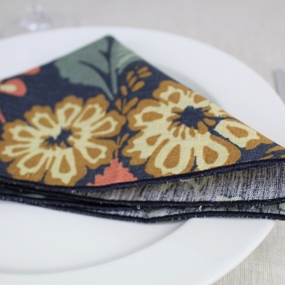 Guardanapo de tecido floral dobrado em prato branco com talheres ao lado