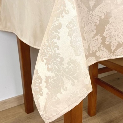 toalha de mesa bege com padrão floral pendurada numa mesa de madeira