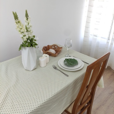 Mesa posta com toalha bege, arranjo floral, pratos, talheres e copo junto a cadeira de madeira