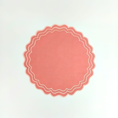 Tapete redondo coral com bordas onduladas sobre fundo branco