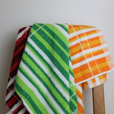 Três toalhas de banho coloridas penduradas numa cadeira de madeira