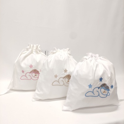 Três sacos de tecido branco com bordados coloridos de nuvem, rapariga e estrelas.