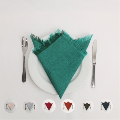 Guardanapo verde com franjas sobre prato branco entre talheres
