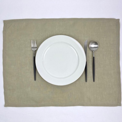 Prato branco com talheres de cabo preto dispostos sobre base de tecido bege