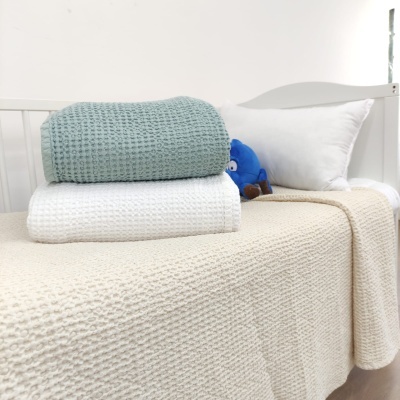 Cama branca com mantas texturizadas e almofada branca