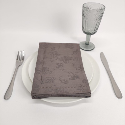 Conjunto de jantar com garfo, faca, prato branco, guardanapo cinzento e copo de vidro verde esmeralda