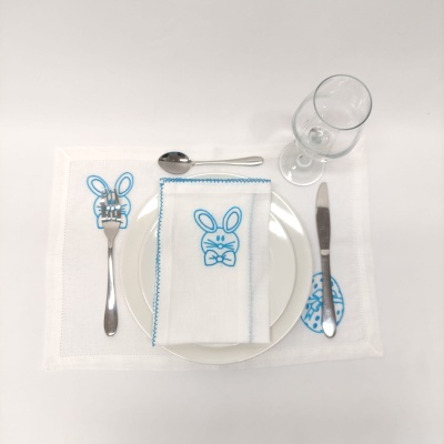 Mesa posta com guardanapo e talheres com bordado e design de coelho azul