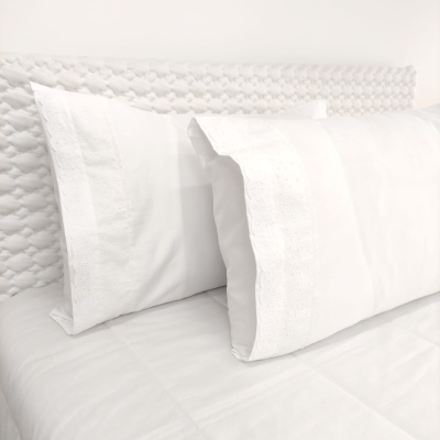 Duas almofadas brancas com fronhas bordadas em cama branca