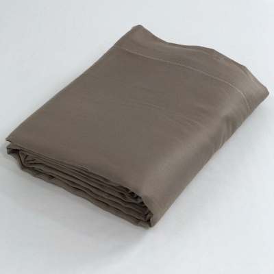 Colcha ou manta castanho claro dobrada em superfície branca