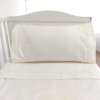 Cama de bebé branca com roupa de cama branca e travesseiro