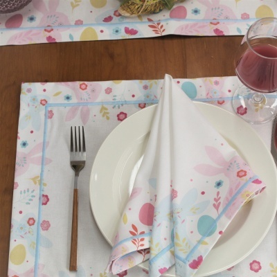 Prato branco com guardanapo floral, garfo com cabo de madeira e copo de vinho, sobre mesa de madeira