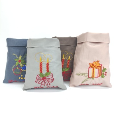 Quatro sacos de tecido com bordados natalícios e texto 'Feliz Natal'