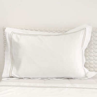 Travesseiro branco com fronhas decoradas com linhas cinzentas na cama branca