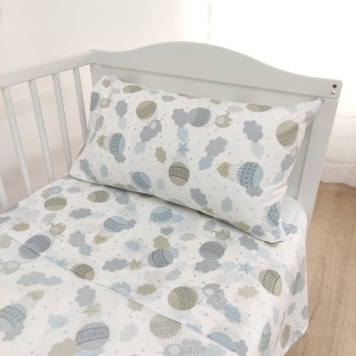 Conjunto de roupa de cama infantil com padrão de balões e nuvens em berço branco
