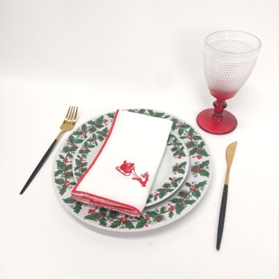 Conjunto de jantar natalício com pratos decorados, guardanapo bordado e copo vermelho