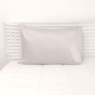 Almofada rosa claro sobre cama branca com cabeceira acolchoada branca