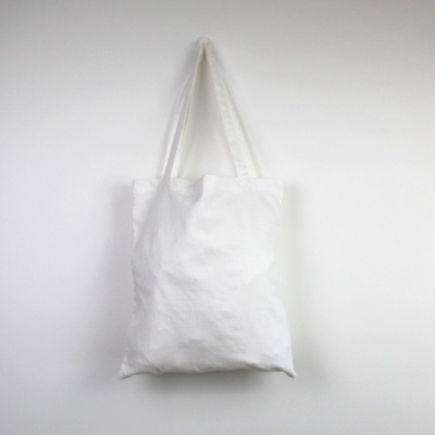 Saco de pano branco simples pendurado numa parede branca