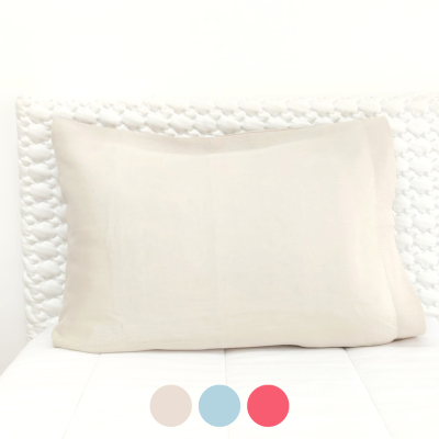 Travesseiro bege claro sobre cama branca com colcha branca e cabeceira entrelaçada branca