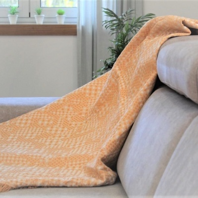 Manta laranja com padrão sobre sofá cinza em sala iluminada