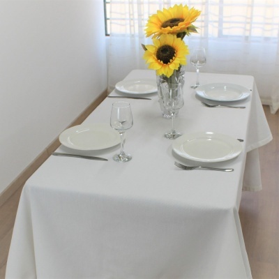 Mesa posta com toalha branca, pratos, copos e vaso com girassóis