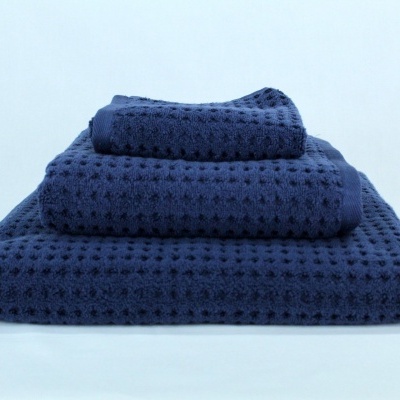 Conjunto de três toalhas azul escuro com padrão quadrado perfurado empilhadas