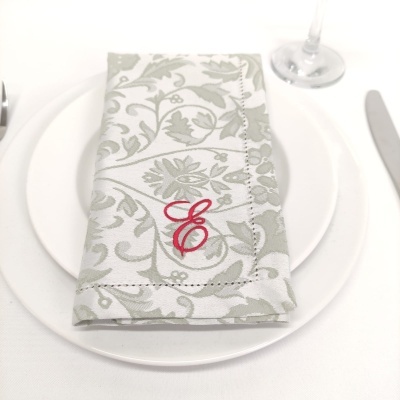 Guardanapo de tecido com bordado em letra vermelha sobre prato branco