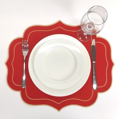 Conjunto de jantar branco com talheres e copo em descanso de mesa vermelho