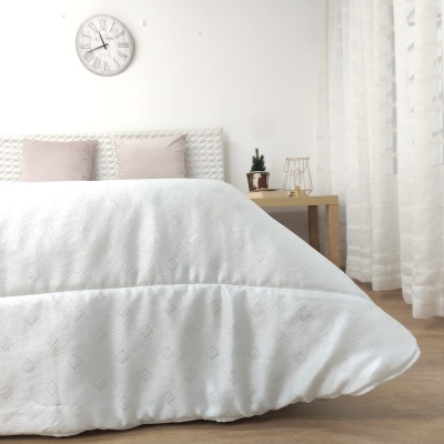 quarto com cama coberta com cobertura branca e almofadas rosa, relógio de parede com números romanos, mesa de cabeceira com decoração