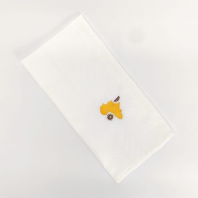 Toalha branca dobrada com bordado amarelo e castanho
