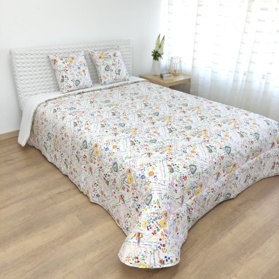 Colcha e almofadas com padrão floral colorido em cama de casal num quarto com chão de madeira