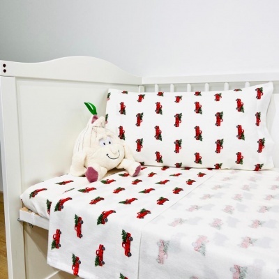 Berço branco com roupa de cama estampada com carros vermelhos e almofada de pelúcia em formato de borboleta