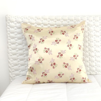 Almofada floral creme sobre cama branca com cabeceira acolchoada