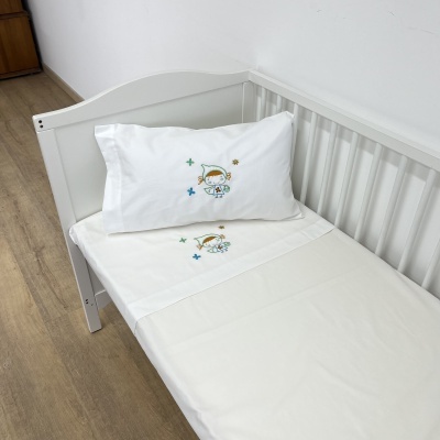 Cama de bebé branca com lençóis brancos bordados com menino astronauta