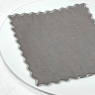 Guardanapo de tecido cinza com borda ondulada sobre prato branco
