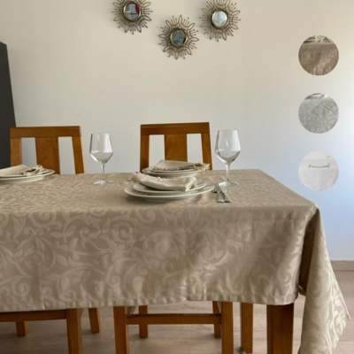 Mesa de madeira com toalha bege floral e decoração de jantar em fundo branco com espelhos redondos