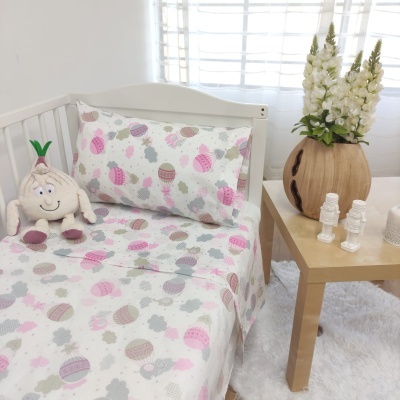 Cama branca com roupa de cama infantil colorida e mesa de madeira com flores e estátuas