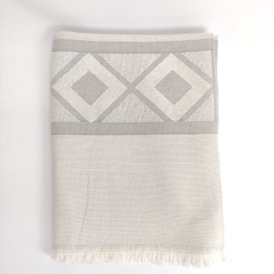 Toalha ou manta dobrada com padrão de losangos em tons de bege