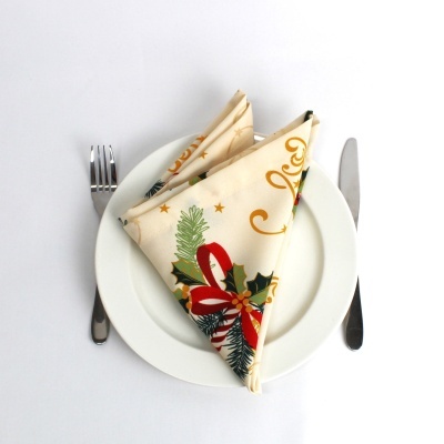 Guardanapo natalício dobrado num prato branco com talheres em fundo branco