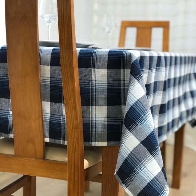 Mesa com toalha xadrez azul e branca, cadeiras de madeira clara