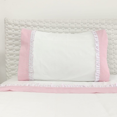 Almofada branca com bordas rosas e lençol branco com faixa rosa sobre cama com cabeceira acolchoada branca