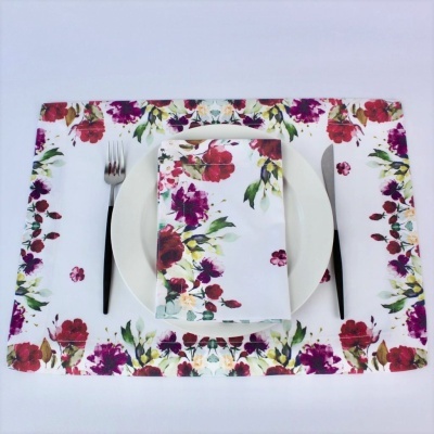 Conjunto de toalha e guardanapo branco com flores coloridas e talheres ao lado de prato branco