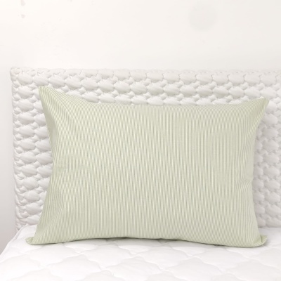 Travesseiro com fronha verde claro e riscada numa cama branca acolchoada
