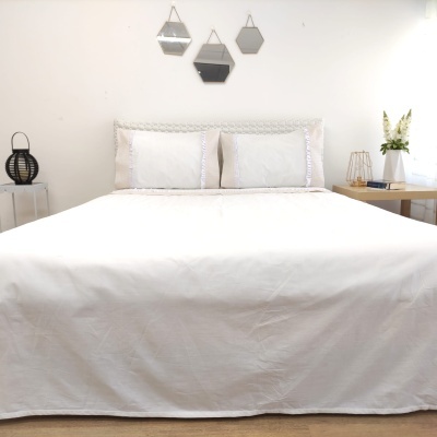 Cama de casal com roupa de cama branca e decoração minimalista