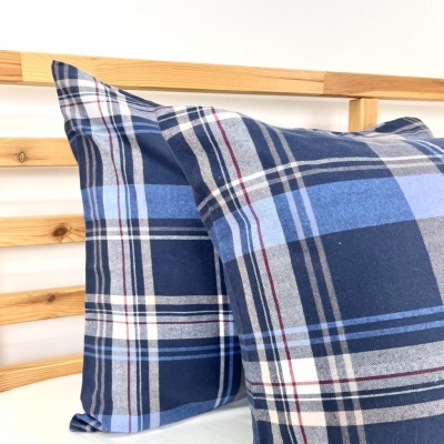 Almofadas xadrez azuis sobre colchão branco com cabeceira de madeira