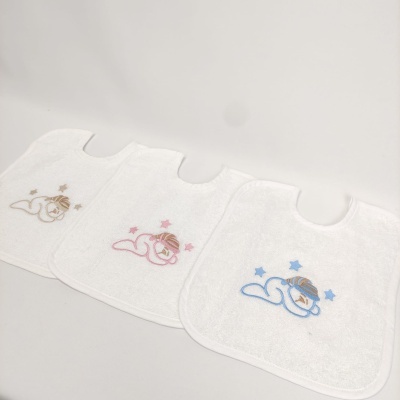 Três babetes brancos com bordados de bebé a dormir em cores castanho, rosa e azul